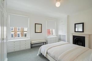 Dormitorio blanco con cama y chimenea en Beautiful maisonette in the heart of Chelsea, en Londres