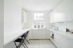 biała kuchnia z blatem i krzesłem w obiekcie Beautiful maisonette in the heart of Chelsea w Londynie