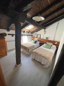 a bedroom with two beds in a room with wooden ceilings at Las Casas de Quintanilla 3 in Quintanilla las Torres