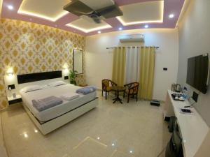 a bedroom with a bed and a desk and a television at Hotel Buddha Park near Sarnath, Varanasi in Varanasi