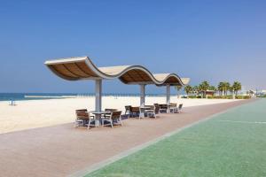 eine Gruppe von Tischen und Stühlen unter einem Pavillon am Strand in der Unterkunft Skylark Hotel Apartments AL Barsha in Dubai