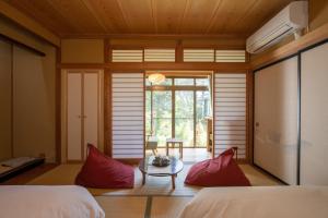 Habitación con 2 camas, mesa y ventana en Kamei no Yu, en Yamanouchi