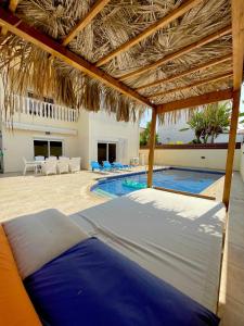 a swimming pool with a bed under a straw roof at Mediterranean Breeze Villa in Protaras