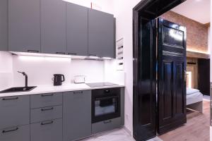 a kitchen with white cabinets and a black refrigerator at Hevals Spa & Design Apartment in Berlin +26 photos