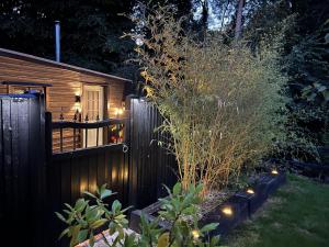 una cerca en un patio con luces encendidas en Charming 1-Bed Lodge in woodland setting, en Great Yarmouth