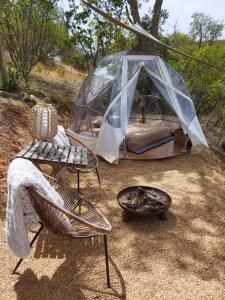 a tent with a bed and a table and a fire pit at Herdade da Maceira in São Luis