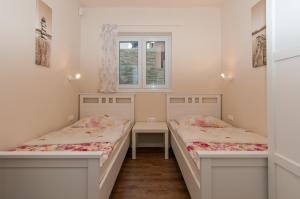two beds in a small room with a window at Villa Sv. Martin in Mali Lošinj