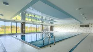 a large swimming pool in a building with windows at Prywatne apartamenty Sun & Snow w Porta Mare Marina z basenem in Dziwnów