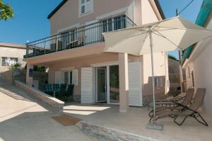 a patio with an umbrella and chairs in front of a house at Villa Sv. Martin in Mali Lošinj