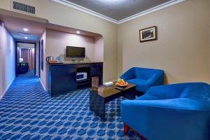 a living room with two blue chairs and a television at Al Bustan Flats in Sharjah