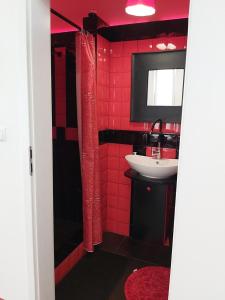 a red bathroom with a sink and a mirror at Apartament Parkowa 2 in Morąg