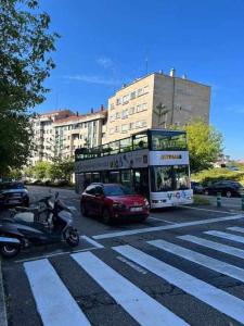 un autobús de dos pisos y un coche rojo en una calle en Mi Refugio, en Vigo