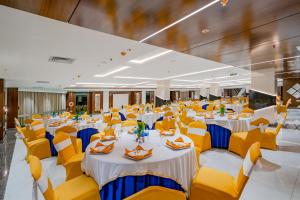 a large banquet hall with tables and yellow chairs at Payel Inn in Āsansol