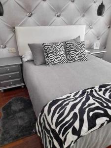 Una cama con almohadas de cebra en un dormitorio en Apartamentos Florida Casablanca, en Vigo