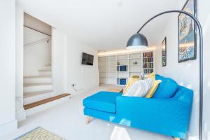 a blue couch in a living room with a staircase at Hidden Gem in Chiswick, Stylish 1 Bedroom House in London