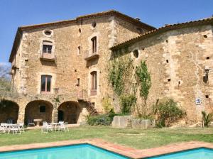 a large stone building with a pool in front of it at Can Traver de Besalú in Maia de Montcal