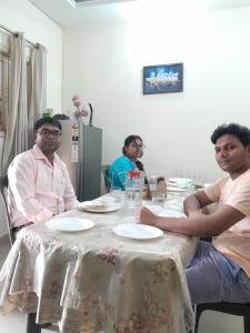 un grupo de hombres sentados en una mesa en Bhagvati BnB Homestay Apt, en Nueva Delhi