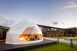a white dome house on a deck with a tennis court at glampark ACONCAGUA RESORTS in Minami Aso
