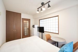 a bedroom with a bed and a table and a refrigerator at Garden Otsuka in Tokyo
