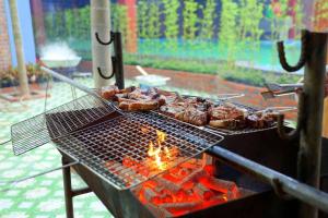 una parrilla con carne y verduras cocinando en ella en Gecko Backpackers Hostel, en Ninh Binh