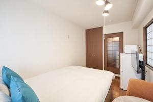 a small room with a bed and a refrigerator at Garden Otsuka in Tokyo