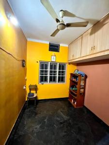 Pokój z wentylatorem sufitowym i żółtą ścianą w obiekcie Chamundi_Temple-Hill View. w mieście Mysuru