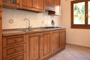 a kitchen with wooden cabinets and a sink and a window at ISA - Residence with swimming pool in Sos Alinos, apartments with air conditioning and private outdoor area in Cala Liberotto