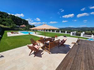 een houten terras met een tafel en stoelen en een zwembad bij Villa Lindenberg Slovakia in Krupina