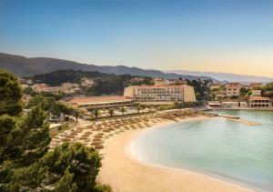 een uitzicht op een strand met parasols en een resort bij Valamar Padova Hotel in Rab