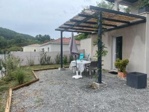 un patio con mesa, sombrilla, mesa y sillas en Les Côteaux de la Grange, en Mercuer