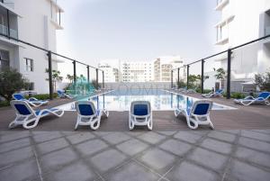 a patio with chairs and a table and a pool at Modern Studio In Oasis in Al Qurayyah