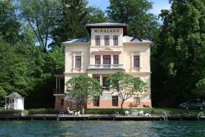 a large white building sitting on the side of a lake at Seeappartements Excelsior in Velden am Wörthersee