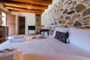 a large bed in a room with a stone wall at Plagia Rooms in Kissamos