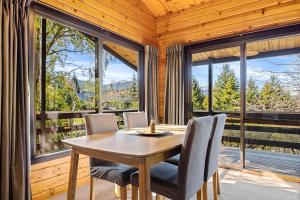 a dining room with a table and chairs and windows at Hanmer Hideaway in Hanmer Springs