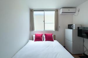 una camera con un letto con due cuscini rosa di Elegant House a Tokyo