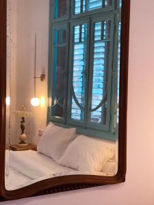 a mirror reflection of a bed with a window at Talpiot Oasis-Louis in Haifa