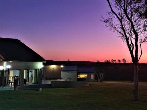 ein Haus bei Nacht mit dem Sonnenuntergang im Hintergrund in der Unterkunft Umbono Private Game Lodge in Alexandria