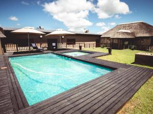 a swimming pool with a wooden deck and a house at Umbono Private Game Lodge in Alexandria