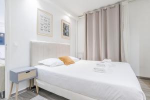 um quarto branco com uma cama branca e uma janela em CMG Anatole France Levallois G em Levallois-Perret