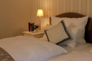 Cama con almohadas blancas y mesa con lámpara en Haus Geistmeier en Lippstadt