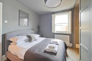 a bedroom with a bed with towels on it at Stylish Family Home by Twickenham Stadium by UnderTheDoormat in London