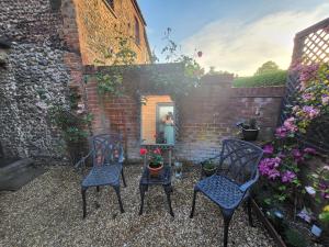 two chairs and a table in a courtyard with a mirror at The Annex in Briston
