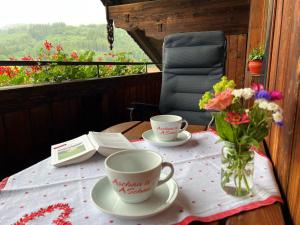 una mesa con dos tazas y un jarrón de flores en Ferienwohnung Bauernhaus Kailhof en Aschau im Chiemgau