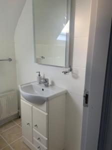 a white bathroom with a sink and a mirror at Connemara Ocean Escape in Galway