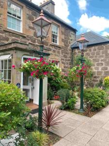 a house with two street lights and flowers in front of it at The Manor House Hotel in Oban