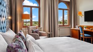 ein Hotelzimmer mit einem Bett, einem Schreibtisch und Fenstern in der Unterkunft Hotel Bayerischer Hof Dresden in Dresden
