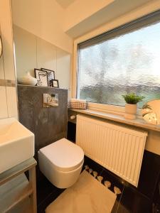a bathroom with a toilet and a sink and a window at Stilvolle 3-Zimmer Wohnung in Ingolstadt mit Balkon und guter Autobahnanbindung in Ingolstadt