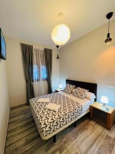 a bedroom with a large bed and a chandelier at HOSPEDAJE CORREDOR DE HENARES in Torrejón de Ardoz +16 photos