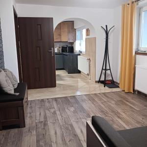 ein Wohnzimmer mit Holzboden und eine Küche in der Unterkunft Apartament Rabinówka in Maruszyna