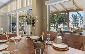 a dining room with a table with wine glasses at Oceans Edge Beach House At Oak Beach in Oak Beach